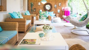 A cozy living room with wicker furniture, a white coffee table, and a hanging chair. - La Pineta Al Mare (Forte dei Marmi)