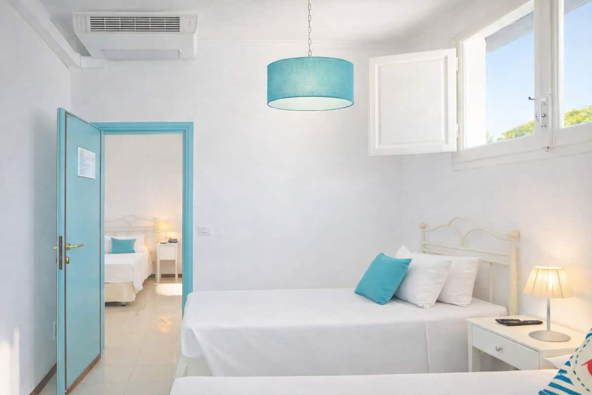 Une chambre à coucher avec un lit, une table de chevet, une lampe et une fenêtre.