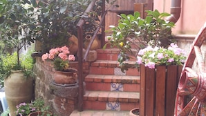 Una escalera con baldosas de terracota, rodeada de macetas con plantas y flores.