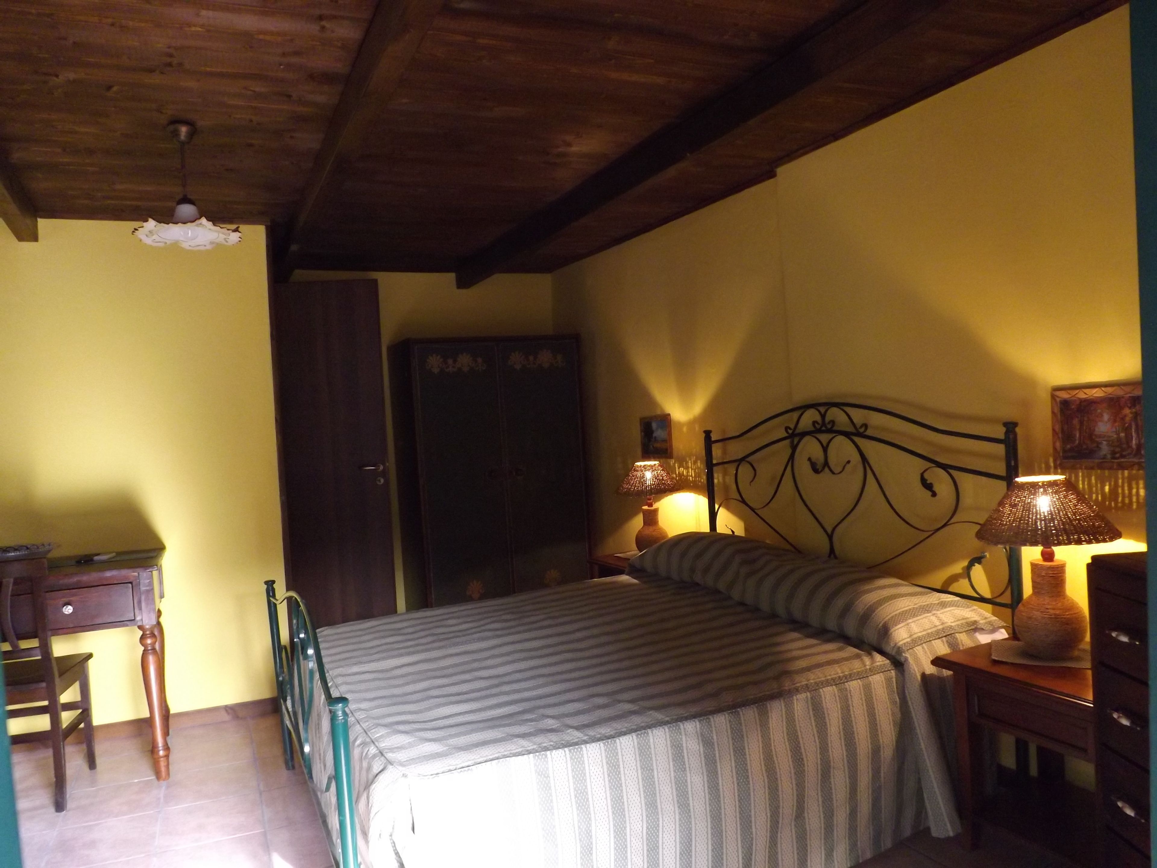 Une chambre à coucher avec un lit, des lampes de chevet, un plafond en bois et un bureau avec une chaise.