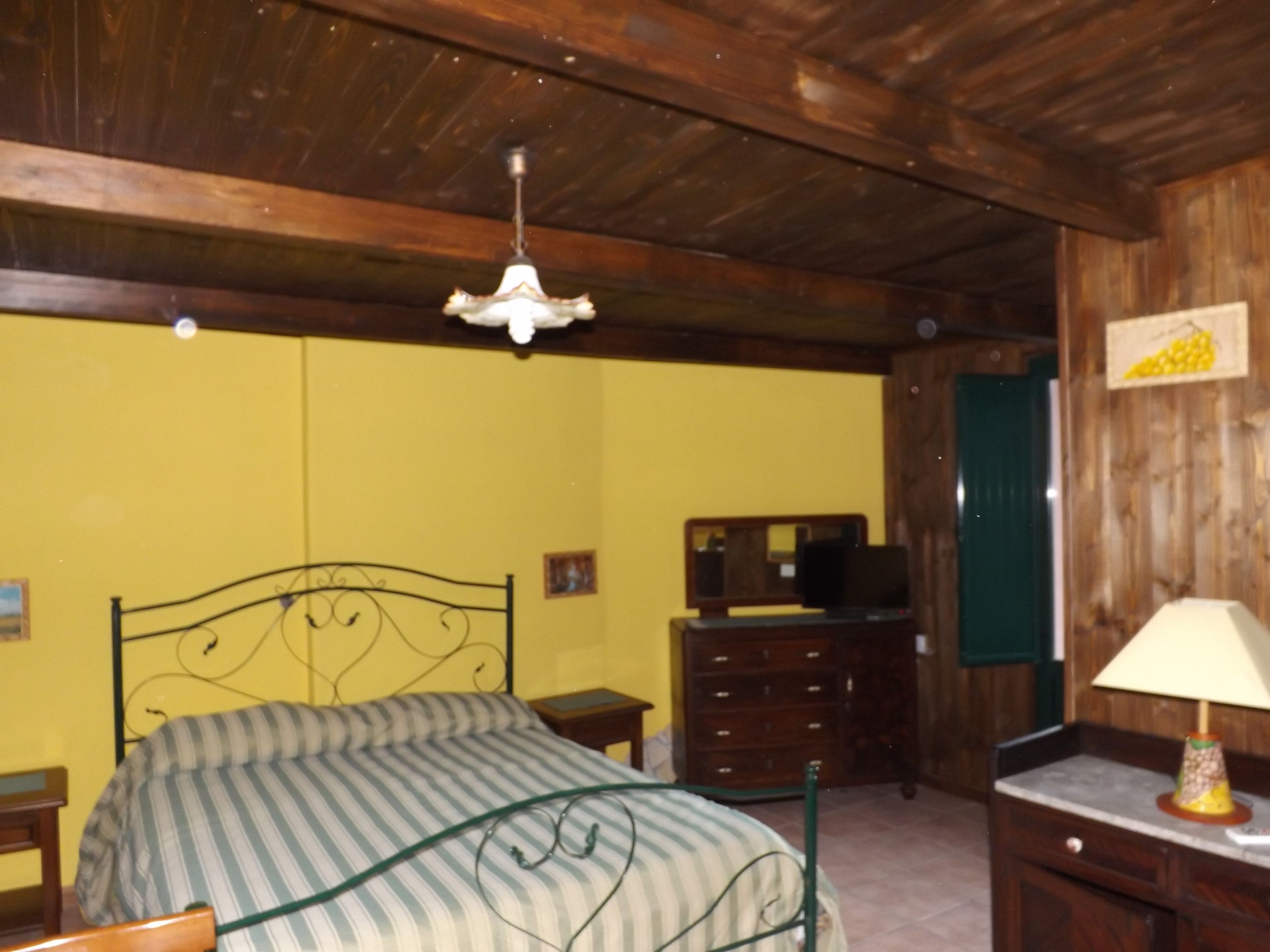 Une chambre avec un lit, une commode, un téléviseur et une lampe.