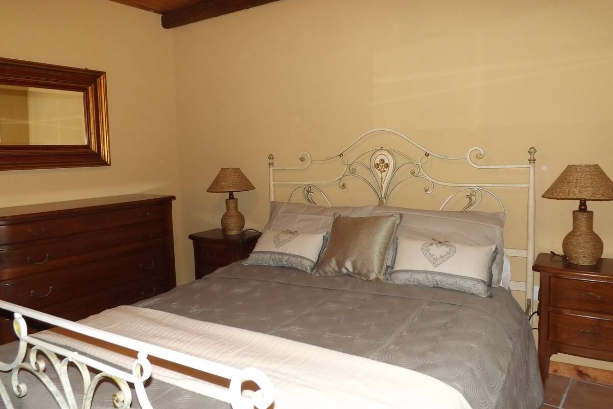A bedroom with a bed, two nightstands, a dresser, and a mirror.