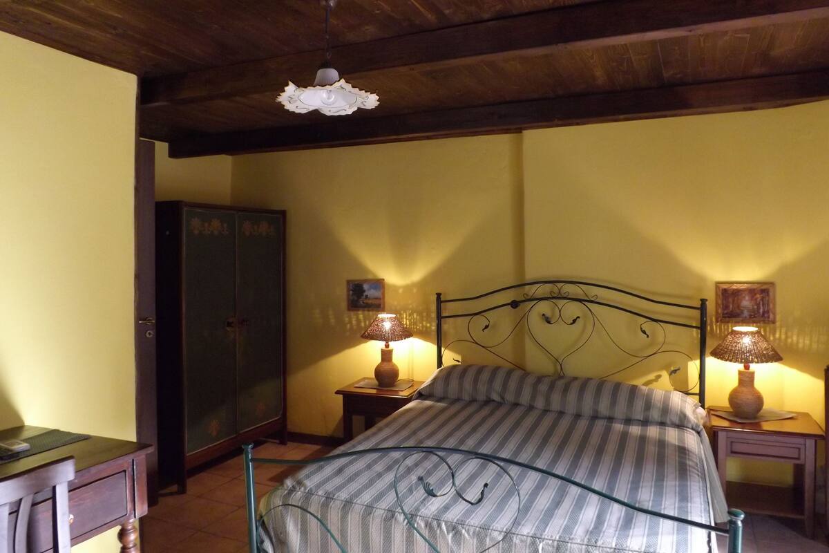 A bedroom with a bed, two bedside tables with lamps, a wardrobe, and a ceiling light fixture.