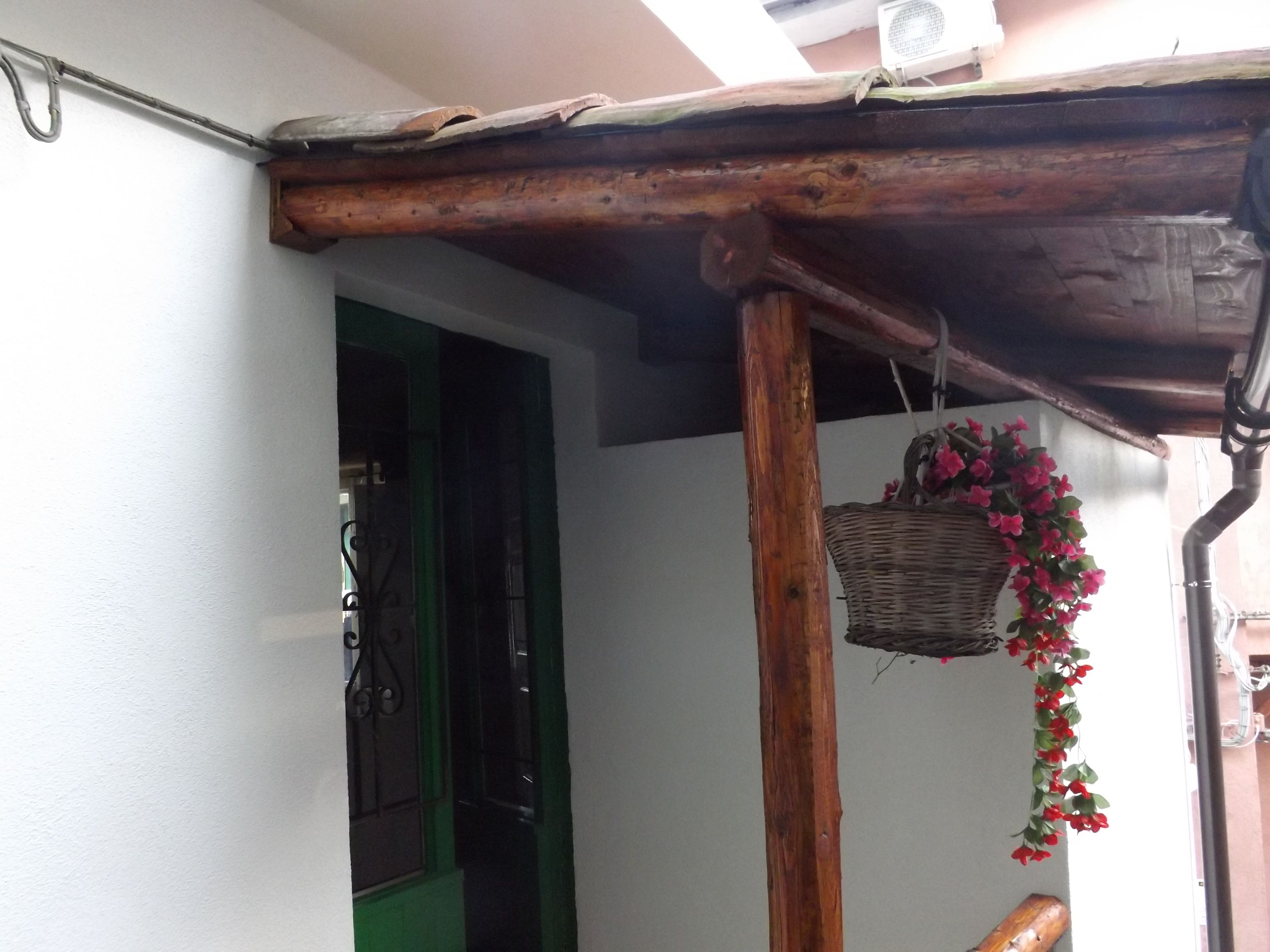 A wooden structure with a basket hanging from a pole, a green door, and a white wall.