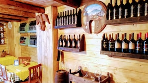 Un interior de madera con estanterías para vino, una mesa de madera con mantel amarillo y un ambiente rústico.