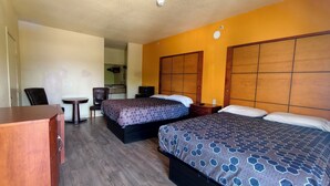 Ein Hotelzimmer mit zwei Betten, einem Schreibtisch, einem Stuhl und einem kleinen Tisch.