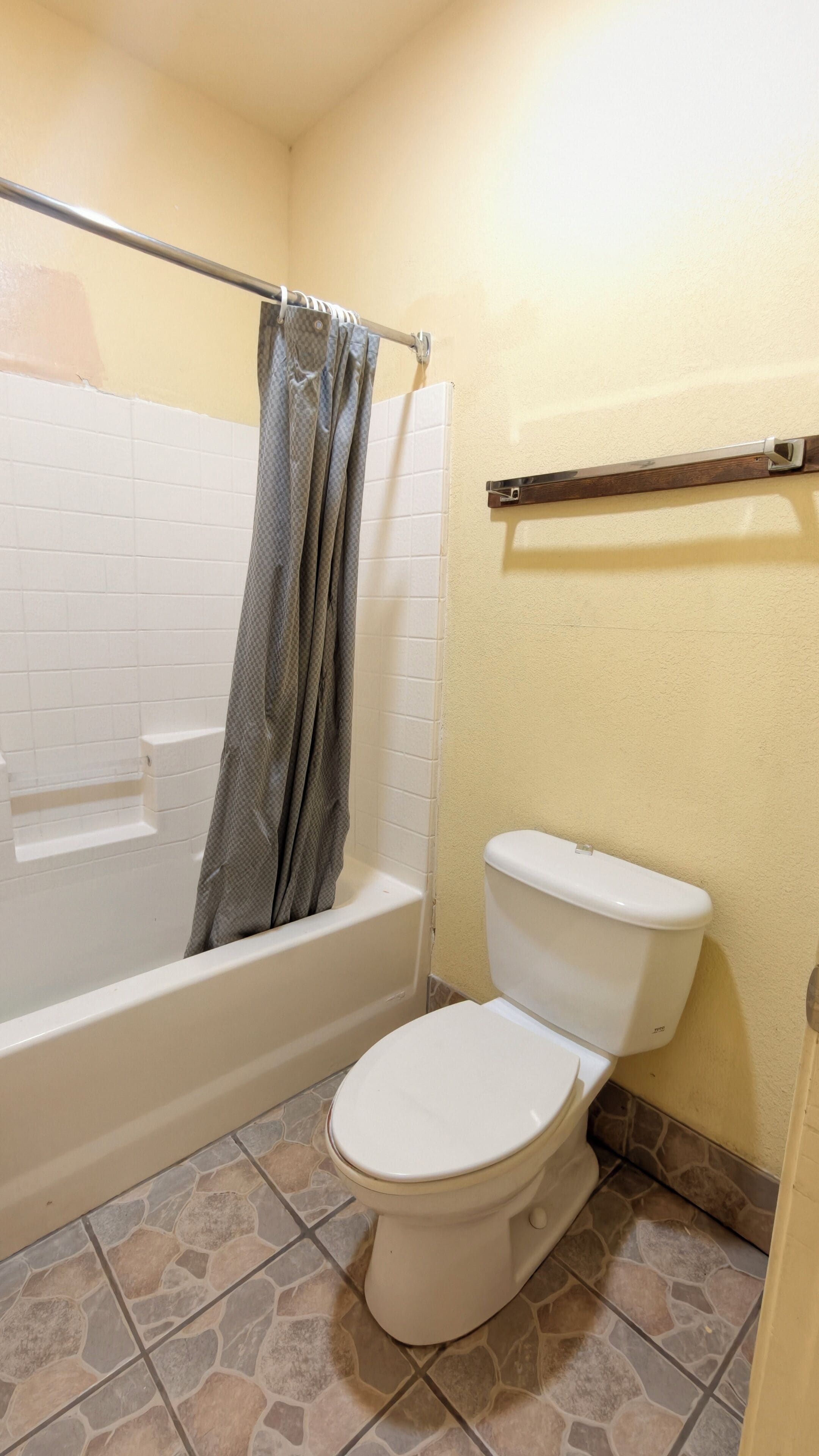 A bathroom with a bathtub, toilet, and a shower curtain.