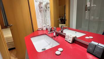 A bathroom with a red countertop, two sinks, a mirror, and a shower area.