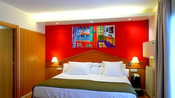 Habitación de hotel con una cama grande, armario de madera, dos mesitas de noche con lámparas, una pared de acento roja y una lámpara de techo.