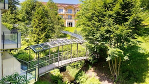 Een modern gebouw met een glazen brug naar een weelderige tuin.