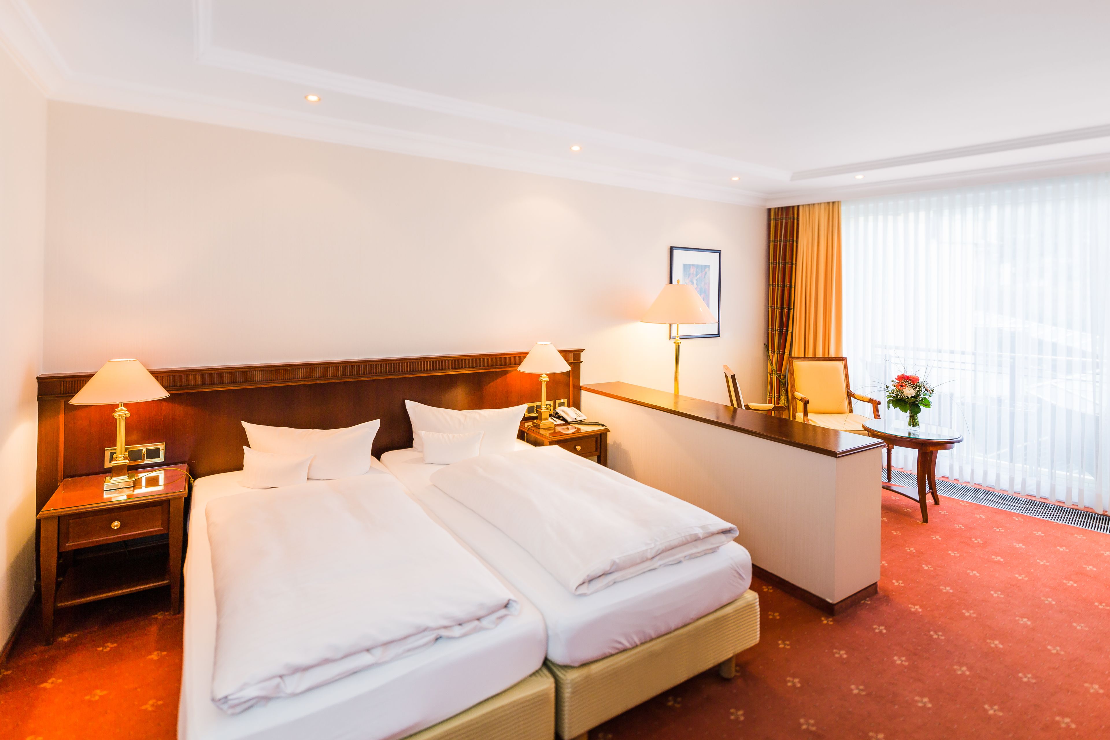 Ein Hotelzimmer mit zwei Betten, einem Schreibtisch und einem fenster mit Vorhängen.