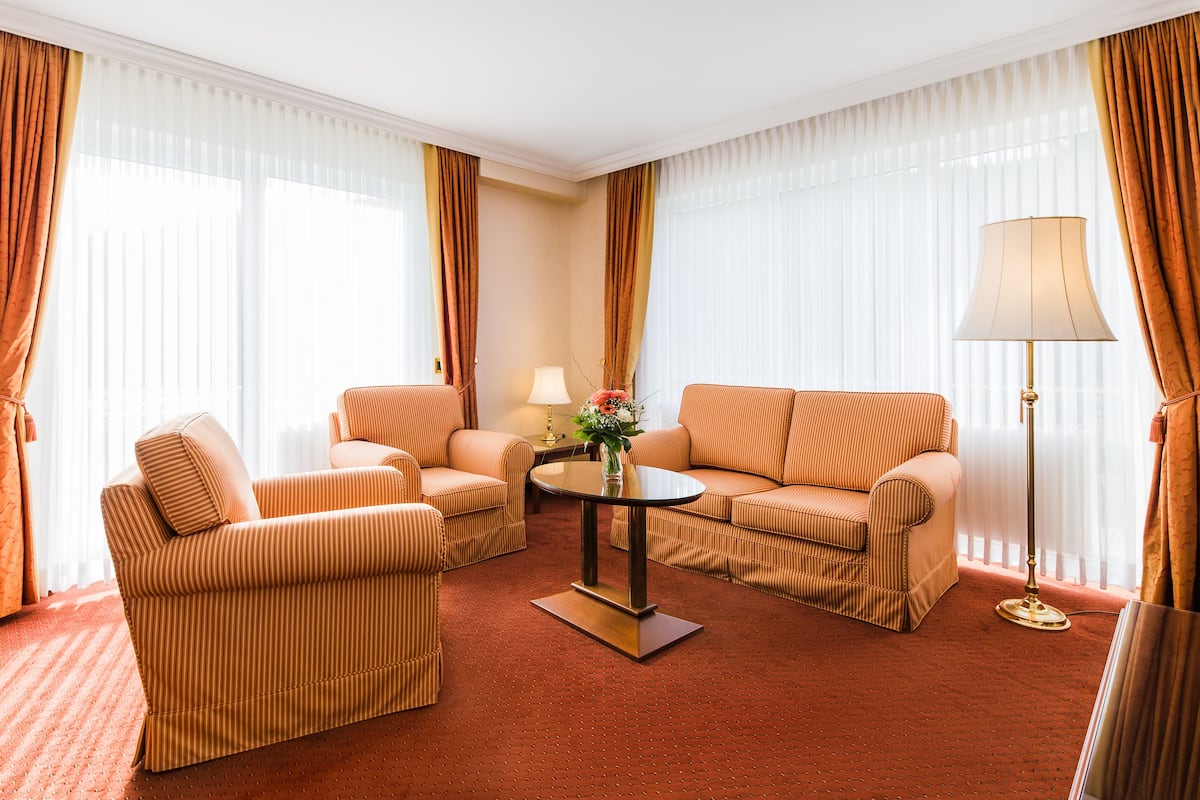 A hotel room with striped sofas, a round coffee table, and a floor lamp.