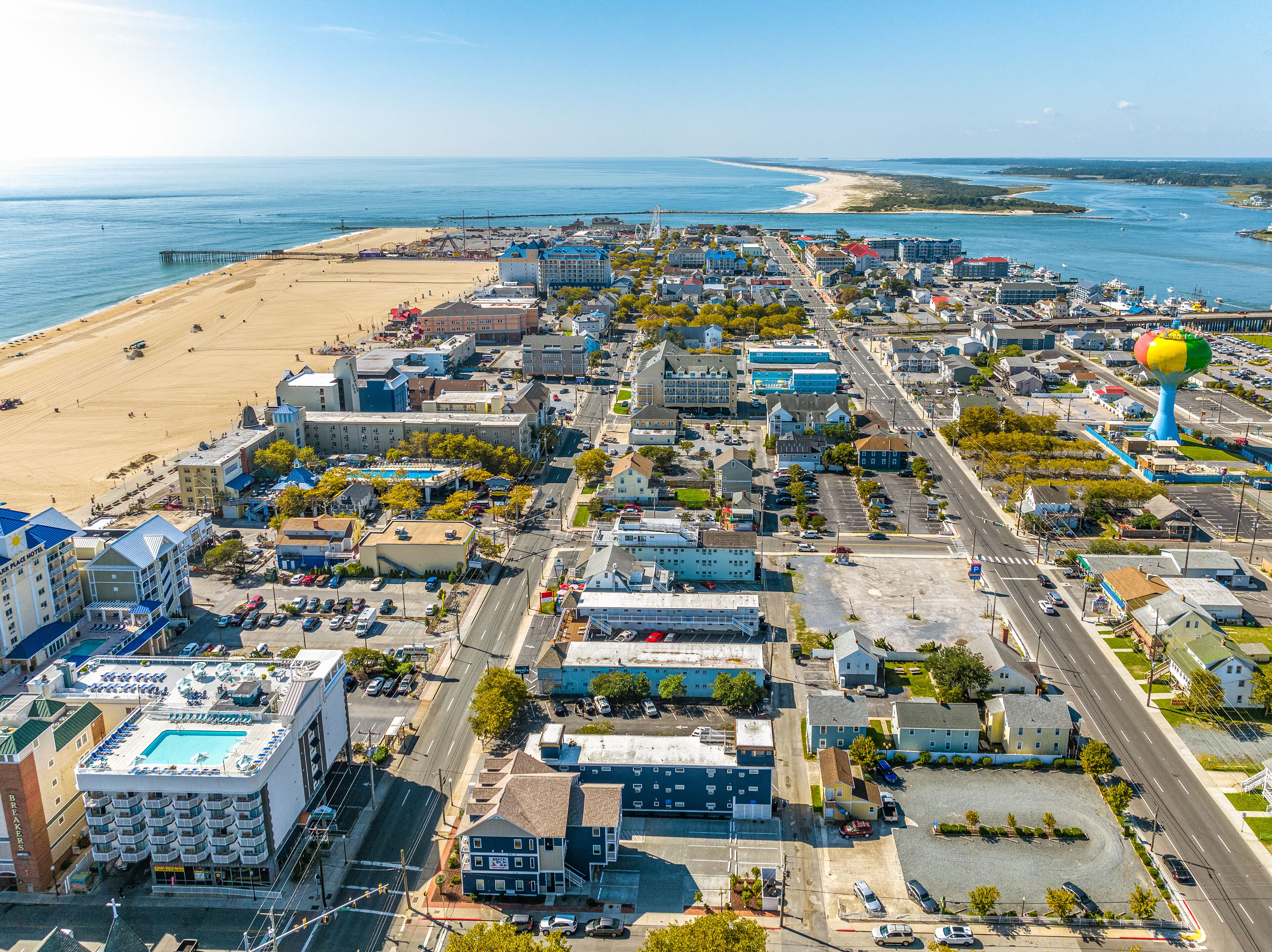 Eine Küstenlandschaft mit Strand, einem Wasserturm und verschiedenen Gebäuden, darunter Hotels und Gewerbegebiete.