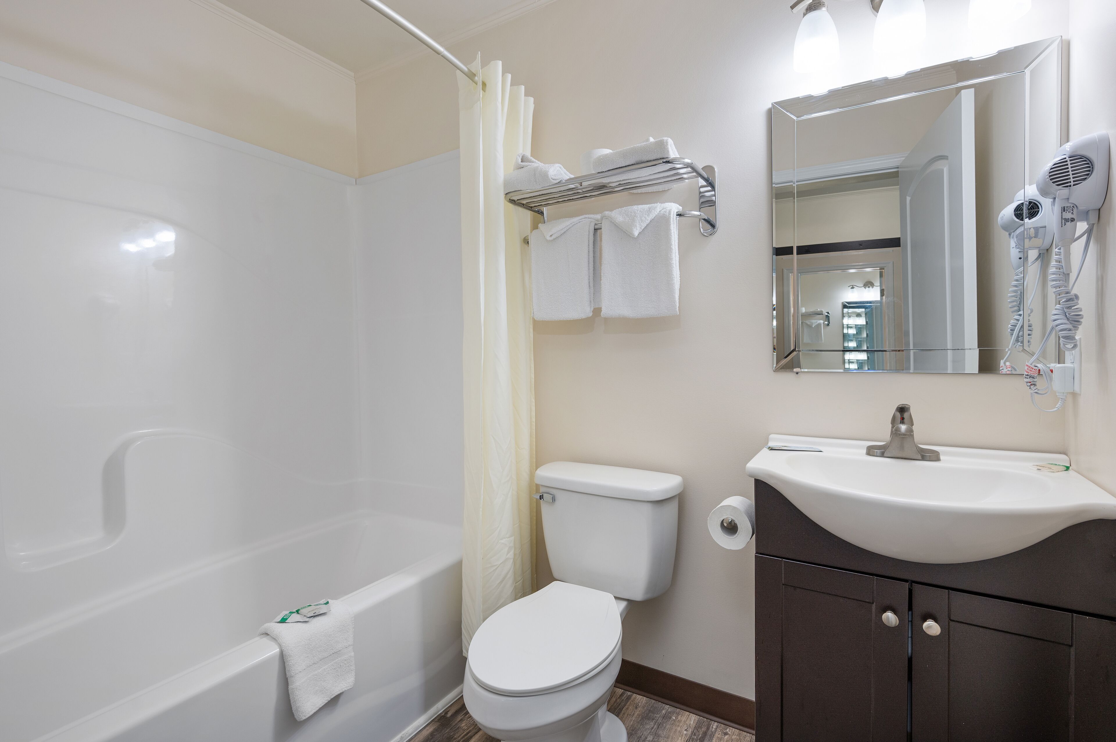 A bathroom with a bathtub, toilet, sink, and a hairdryer mounted on the wall.