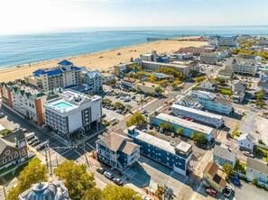 An aerial view of a coastal town with a prominent hotel, a beach, and various buildings. - Beach Bum Inn (Ocean City)