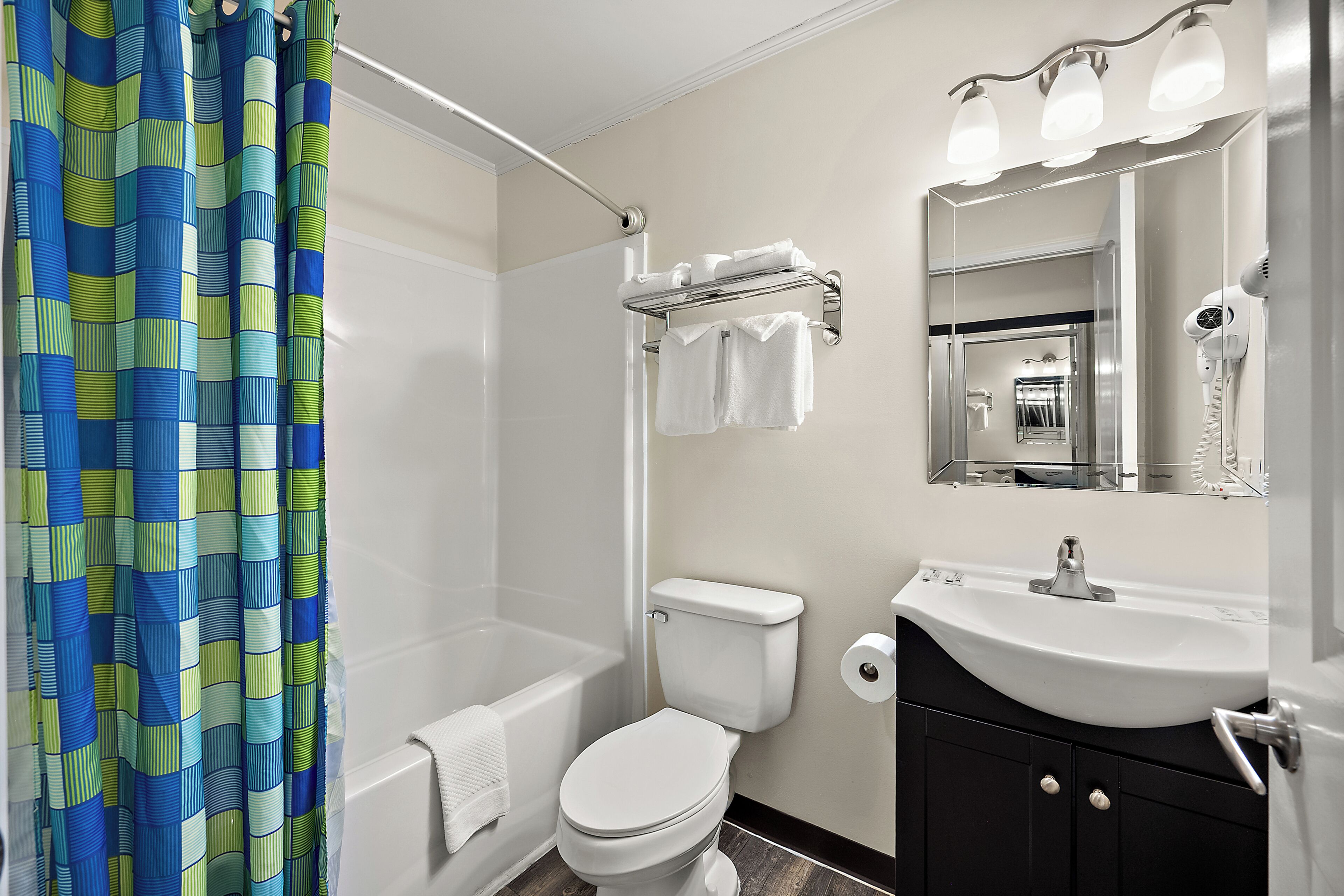 A bathroom with a shower, toilet, sink, and a mirror.