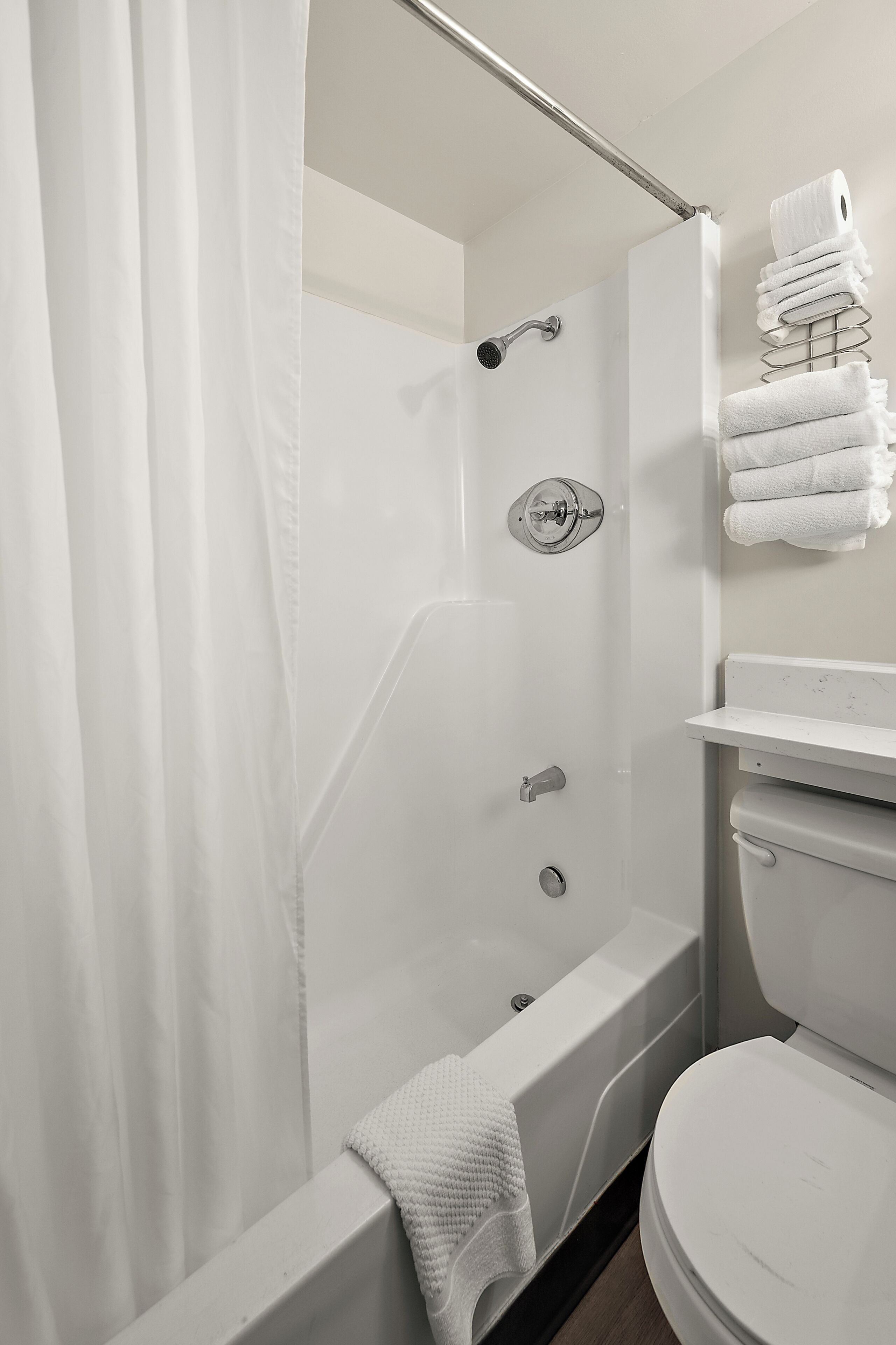 Un baño con ducha, inodoro y perchero para toallas.