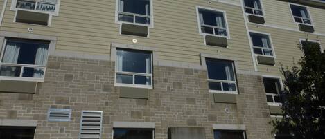 A multi-story building with a beige exterior, multiple windows with white frames, and air conditioning units.