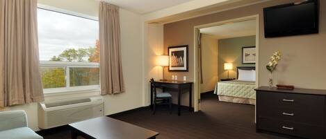 Une chambre d’hôtel équipée d’un lit, d’un bureau, d’une chaise, d’une télévision et d’une fenêtre avec des rideaux.