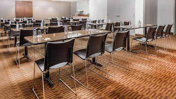 A conference room with multiple tables and chairs, equipped with water bottles and notepads.