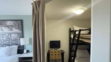 Ein Hotelzimmer mit Etagenbett, Schreibtisch mit Computer, Stuhl und Bett mit weißer Bettwäsche.