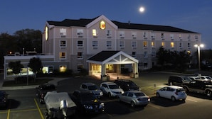 Un hotel de varios pisos con una entrada central y un estacionamiento.