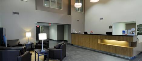 A modern reception area with a wooden counter, black leather seating, and pendant lighting.