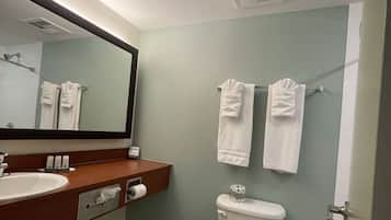 Un baño con lavamanos, espejo, toallero, inodoro y una puerta.