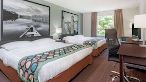 Habitación de hotel con dos camas, un escritorio, una silla y un ventanal grande.