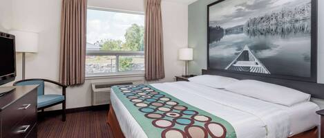 Une chambre d’hôtel avec un grand lit, un bureau, une chaise, une télévision, une fenêtre avec des rideaux et un tableau représentant un lac.