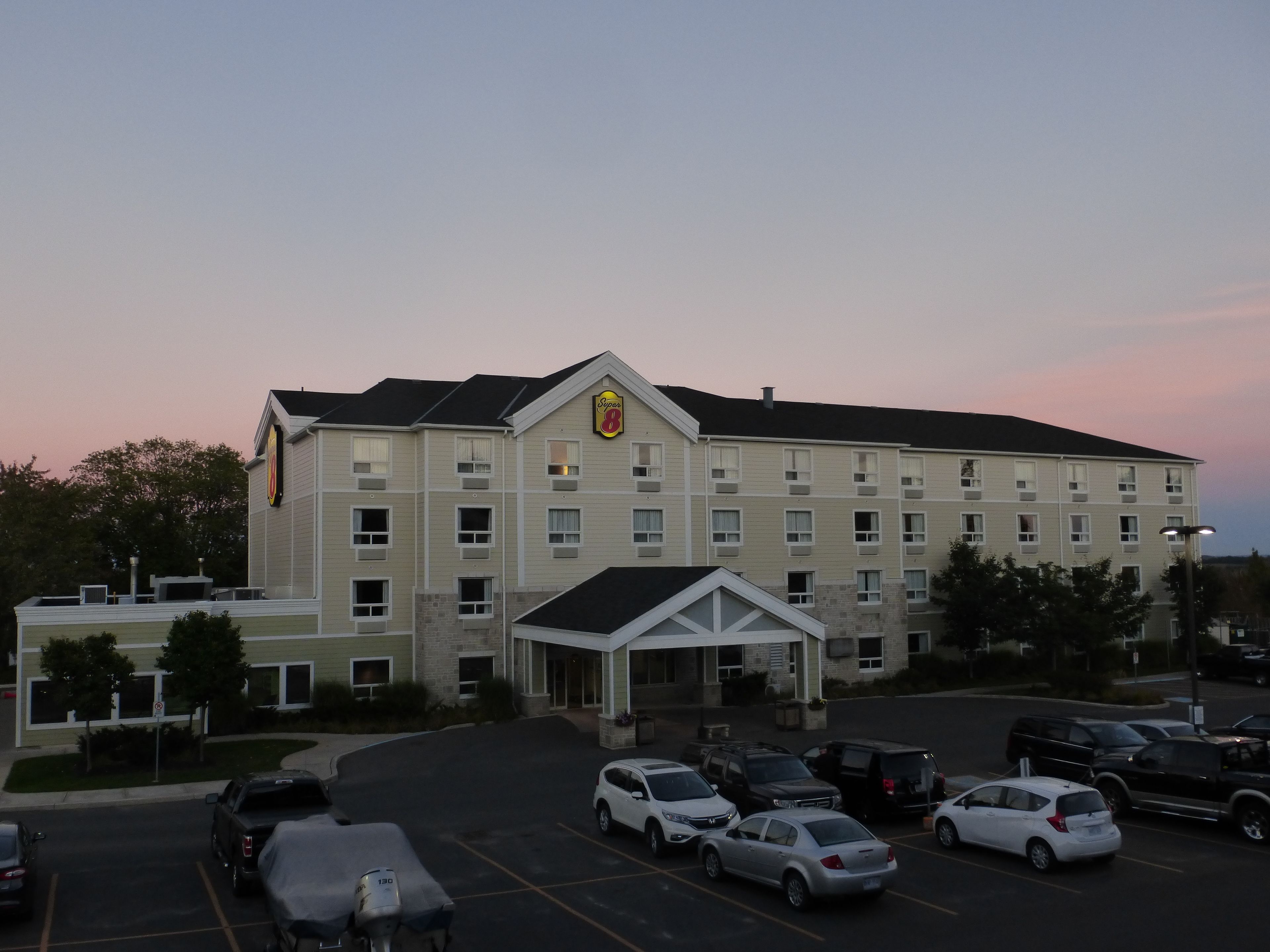 A multi-story hotel with a central entrance, parking lot, and a sign indicating it is a Super 8 hotel.