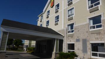 A multi-story hotel with a covered entrance, stone facade, and a prominent sign on the roof.