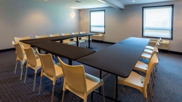 A conference room with a long table and chairs, large windows, and a carpeted floor.