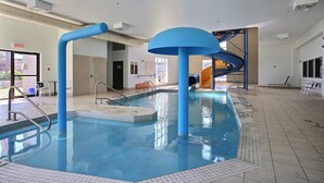 Ein Hallenbad mit einer blauen Rutsche, gefliestem Boden und einem Schild mit der Aufschrift 'SORTIE'.