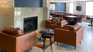 Eine geräumige Lobby mit Ledersofas, einem Kamin, abstrakter Kunst und einer Wanduhr.