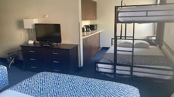 Habitació d'hotel amb literes, escriptori amb televisió, petita cuina i estriatge de llit amb disseny.