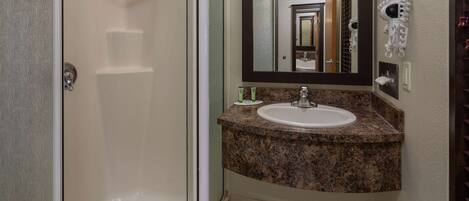 A bathroom with a shower, sink, and mirror.