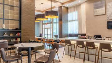 Un moderno vestíbulo de hotel con una zona de bar, asientos y una estantería.