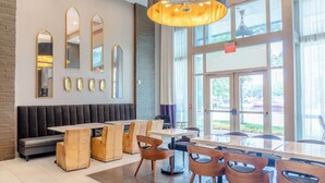 Un interior de restaurante moderno con una barra larga, sillas de madera y una zona de asientos con bancos.