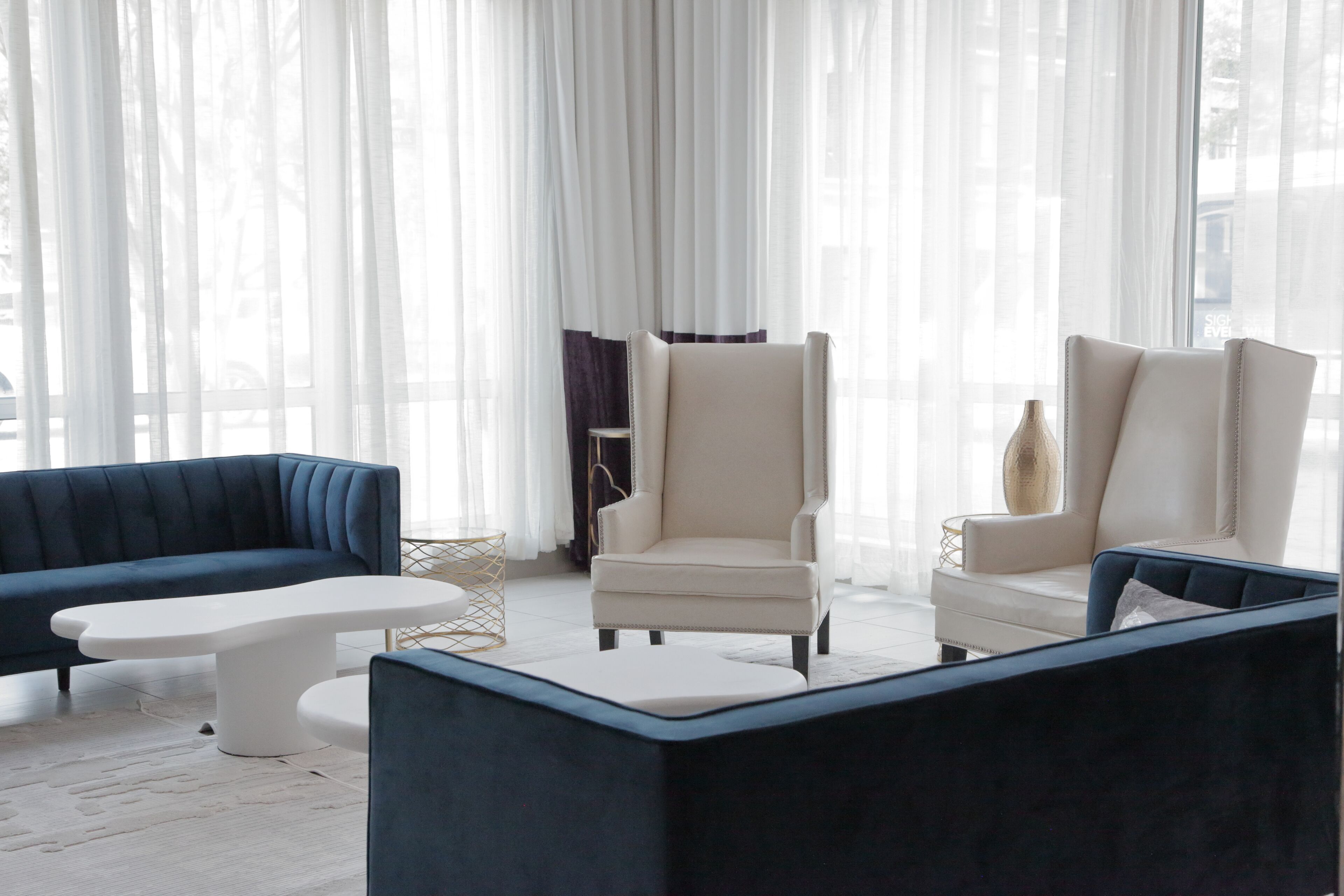 A modern living room with a blue sofa, a white armchair, and a matching ottoman.