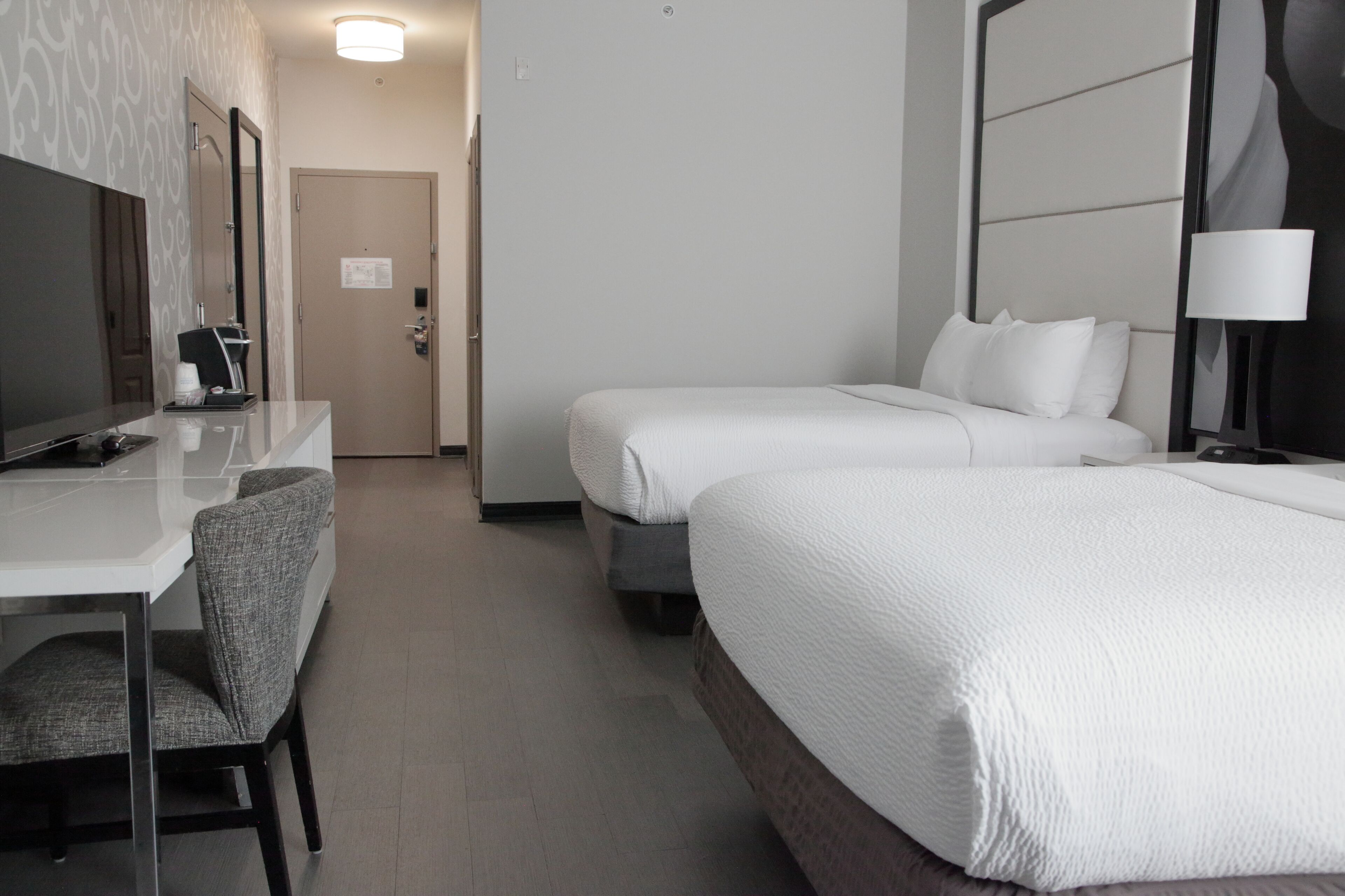 Een hotelkamer met een bed, bureau, stoel, televisie en spiegel.