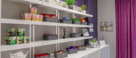 Een receptiezone met planken waarop snacks, manden en potplanten staan.