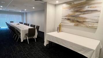 Un salón de conferencias con una larga mesa, sillas y un cuadro abstracto grande en la pared.