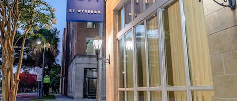 A building with a large illuminated sign reading "TRYP BY WYNDHAM" and a well-lit entrance with large windows.
