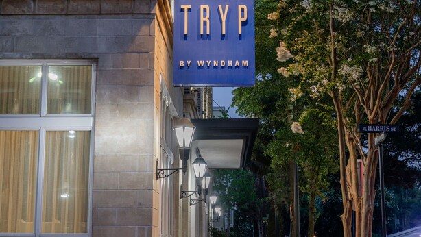 Un edificio con un cartel que dice "TRYP BY WYNDHAM" y una señal de calle que indica "W. HARRIS ST."