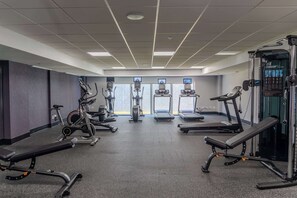 Un gimnasio con cintas de correr, elípticas y equipo de levantamiento de pesas.