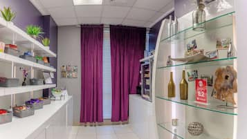 A hotel reception area with purple curtains, shelves with various items, and a glass display case with decorative objects.