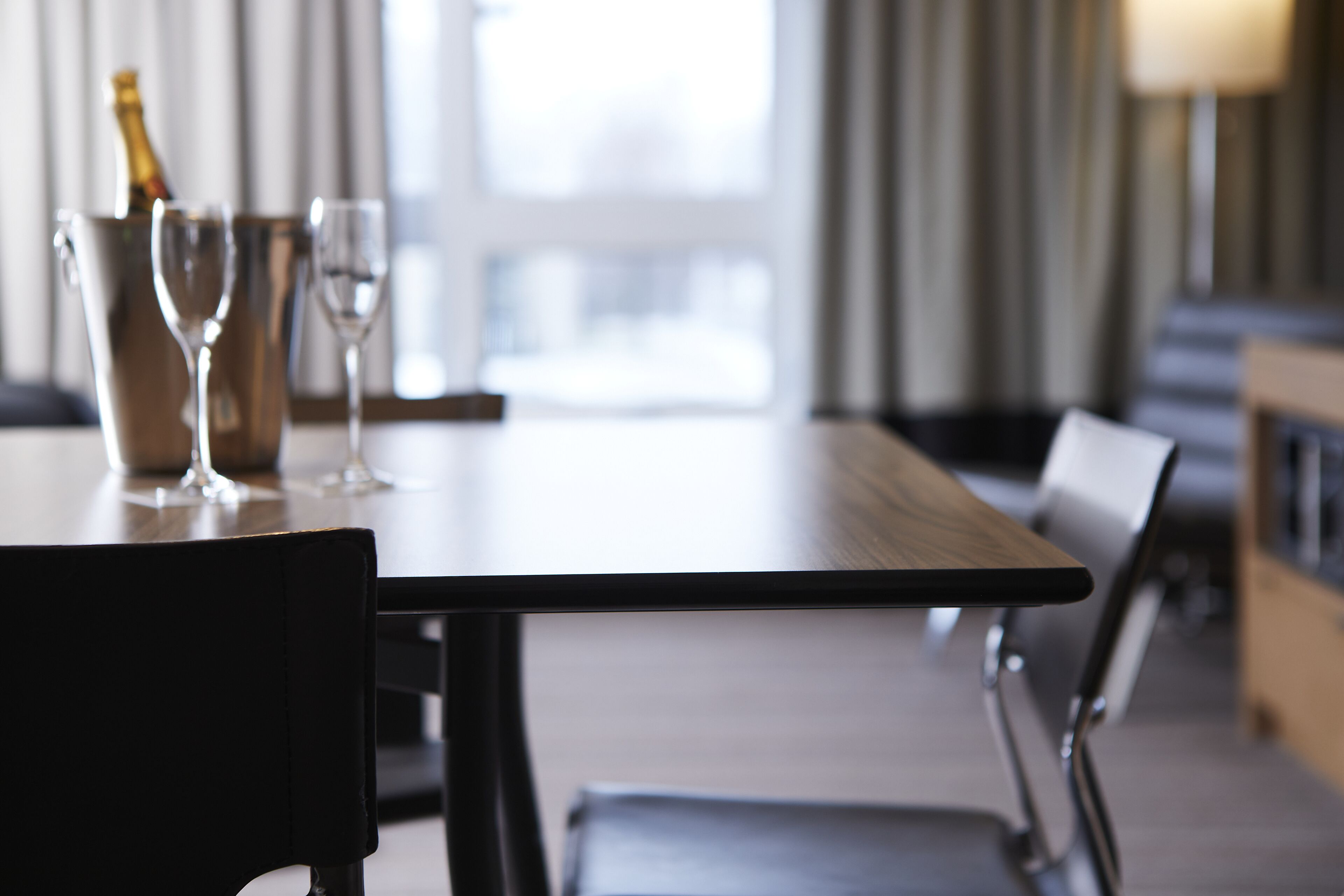 A hotel dining area with a table set for two, a champagne bottle, and two wine glasses.