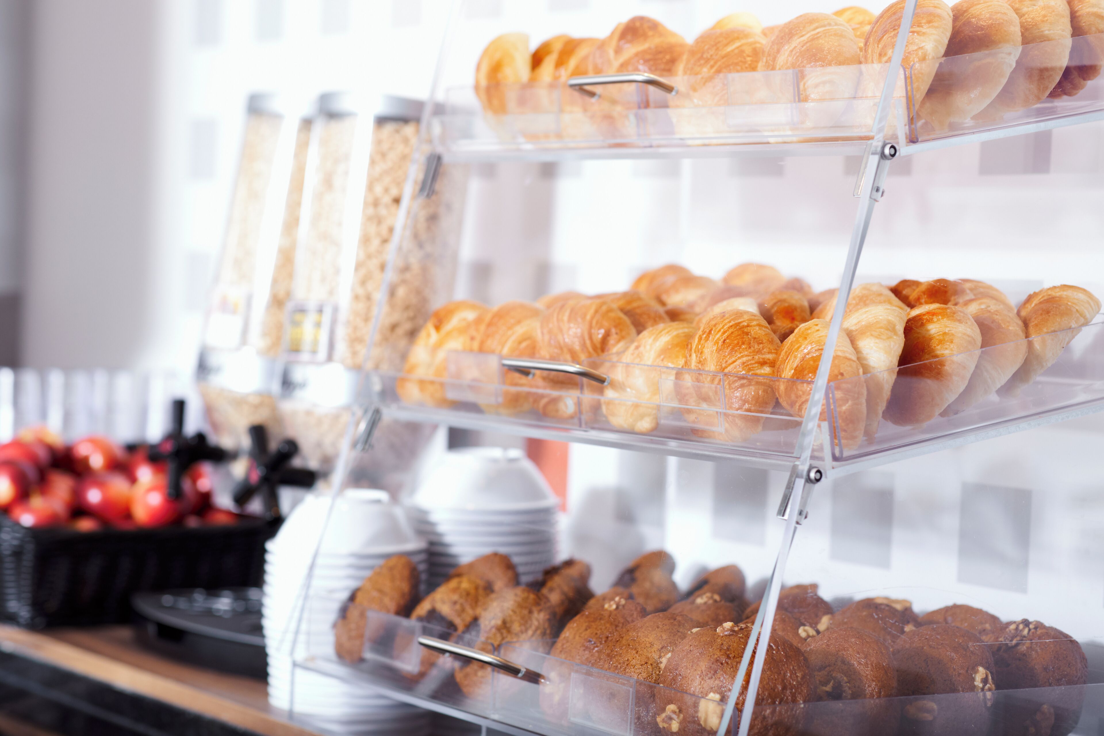 A bakery display with various baked goods, including croissants and muffins, arranged on clear shelves.