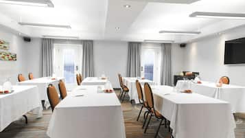 Une salle de conférence équipée de plusieurs tables, de chaises et d’un grand écran.